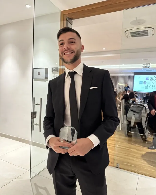 Stephen Ellul in a black suit holding a glass award at the JCI Malta TOYP night, 2023